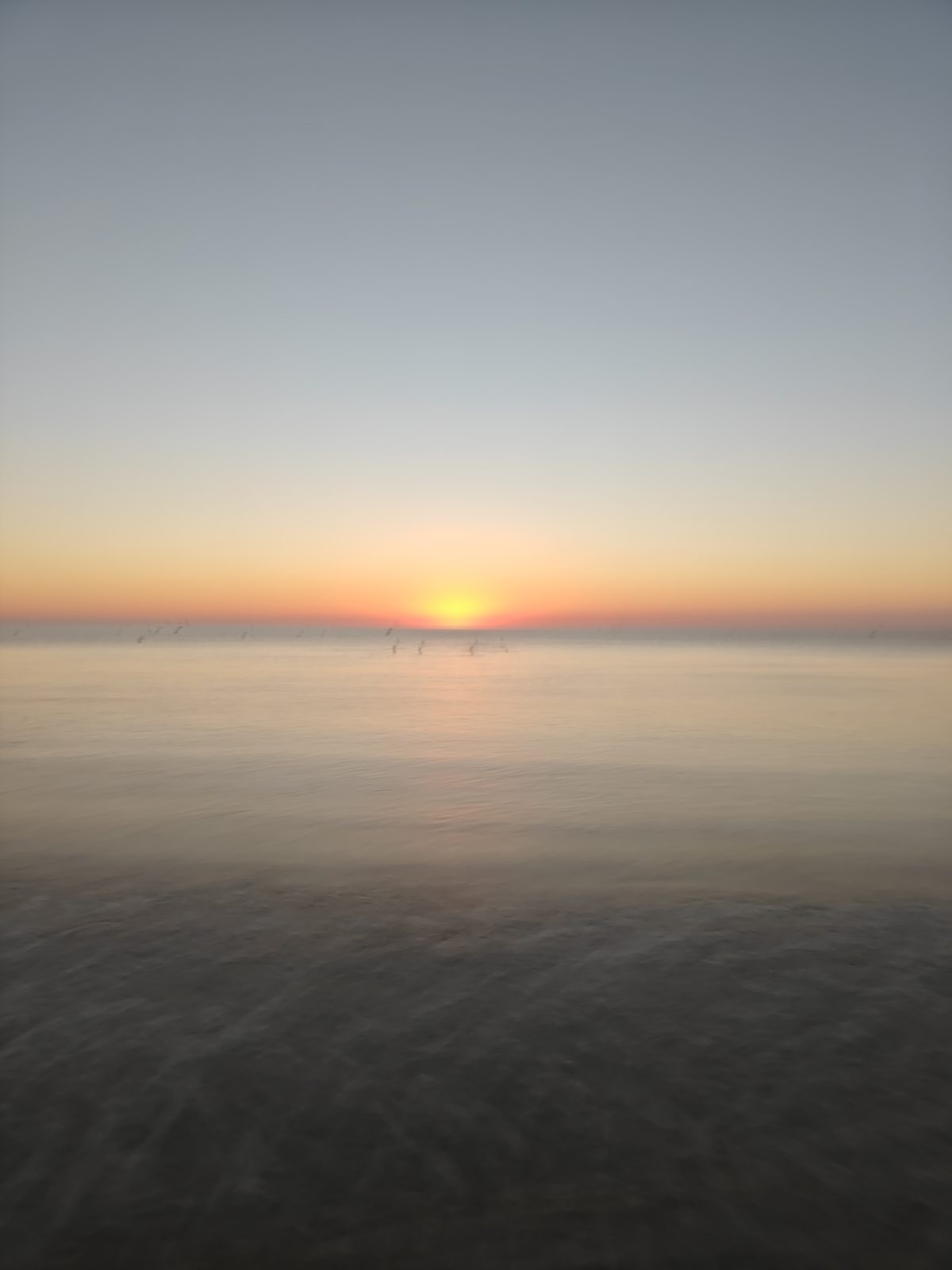 A glassy sea reflecting the rising sun at La Zenia beach
