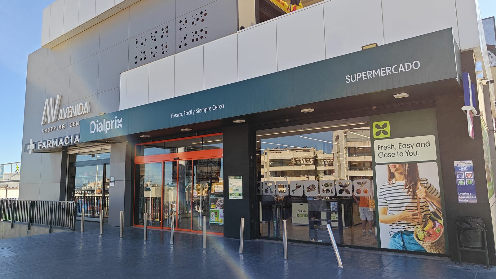 Supermarket entrance, with a pharmacy sign alongside, in Los Dolses